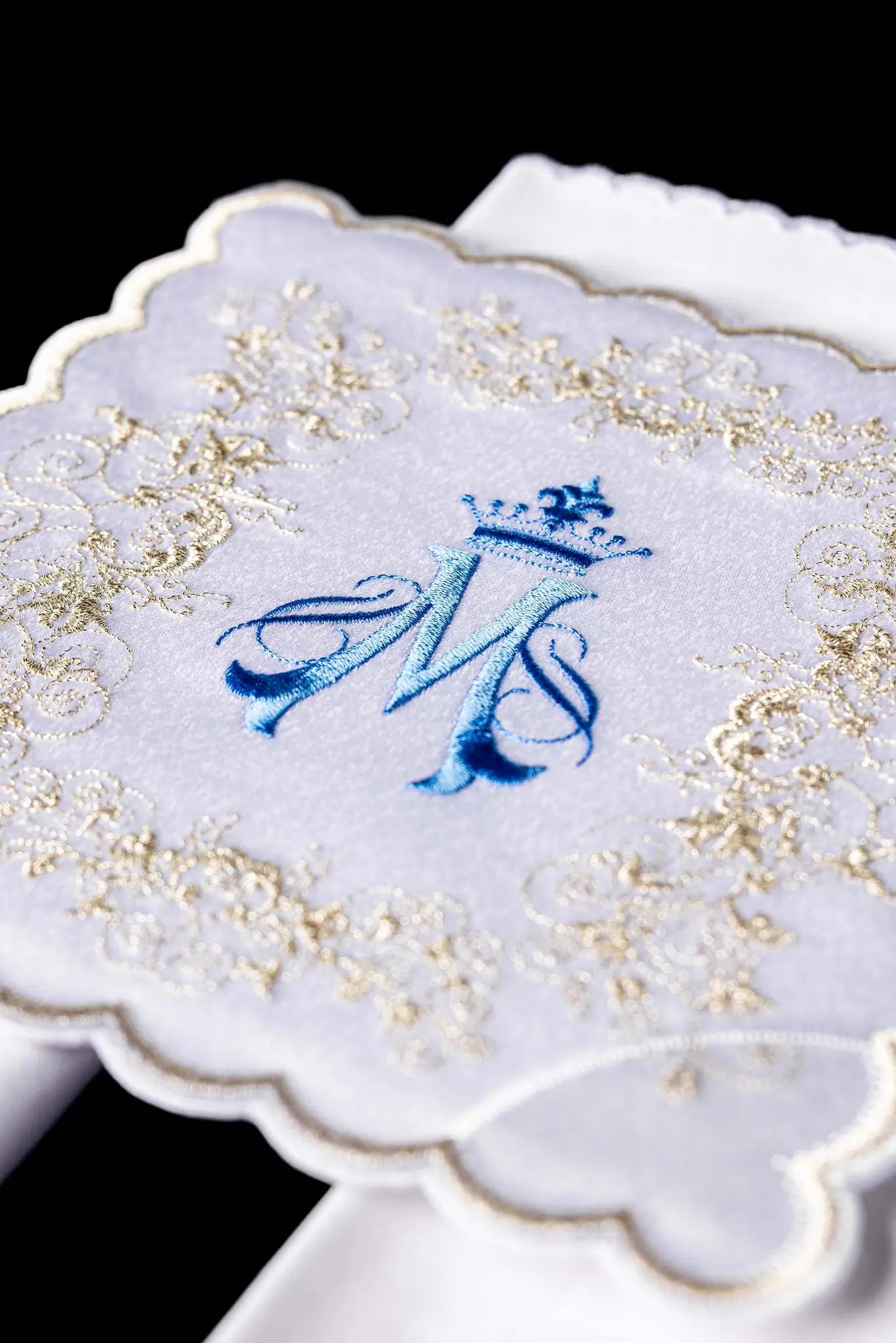 White chalice linen set with Marian monogram embroidery in blue and gold, including pall, corporal, purificator, and lavabo towel.
