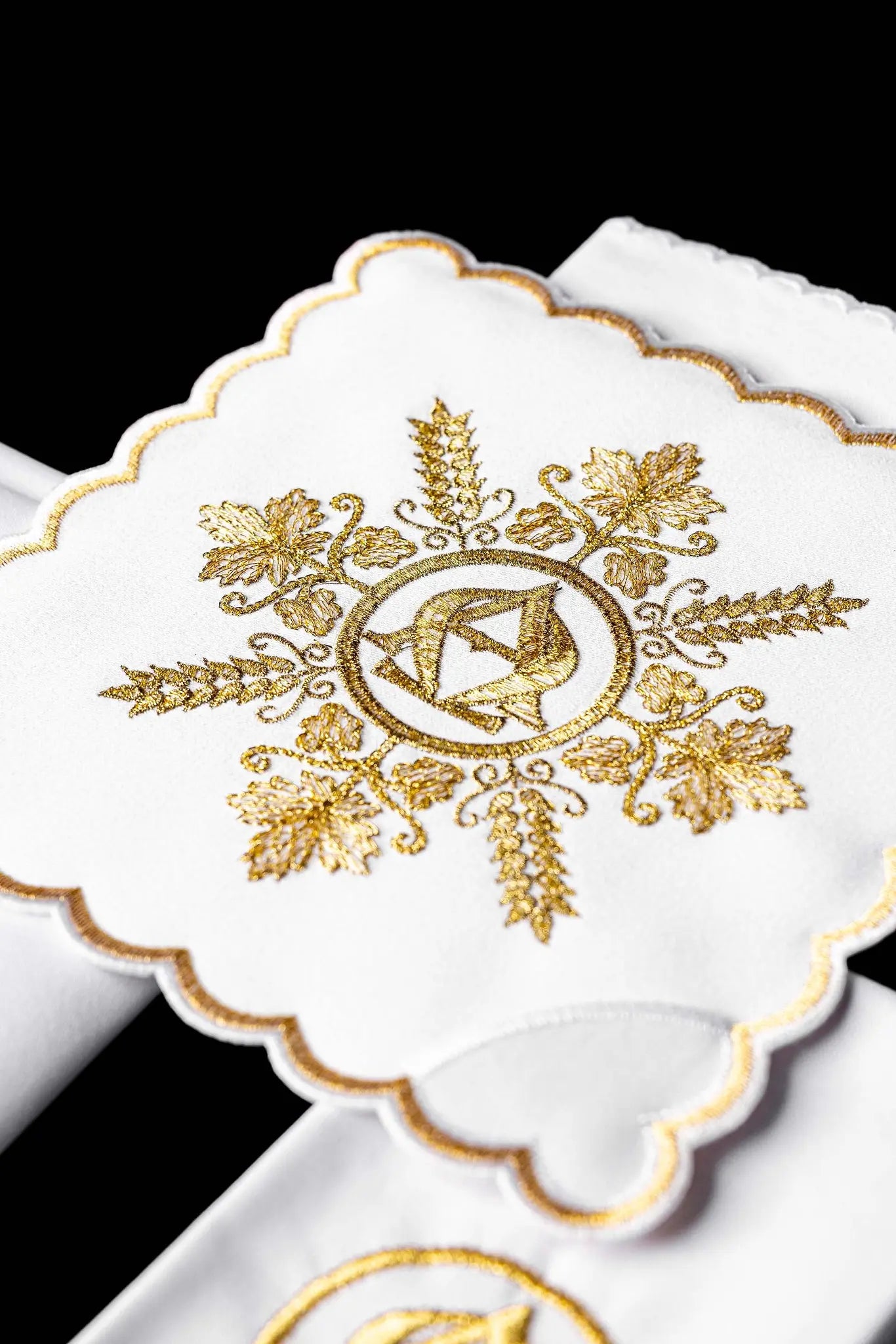 White chalice linen set with gold Alpha and Omega embroidery, including pall, corporal, purificator, and lavabo towel.