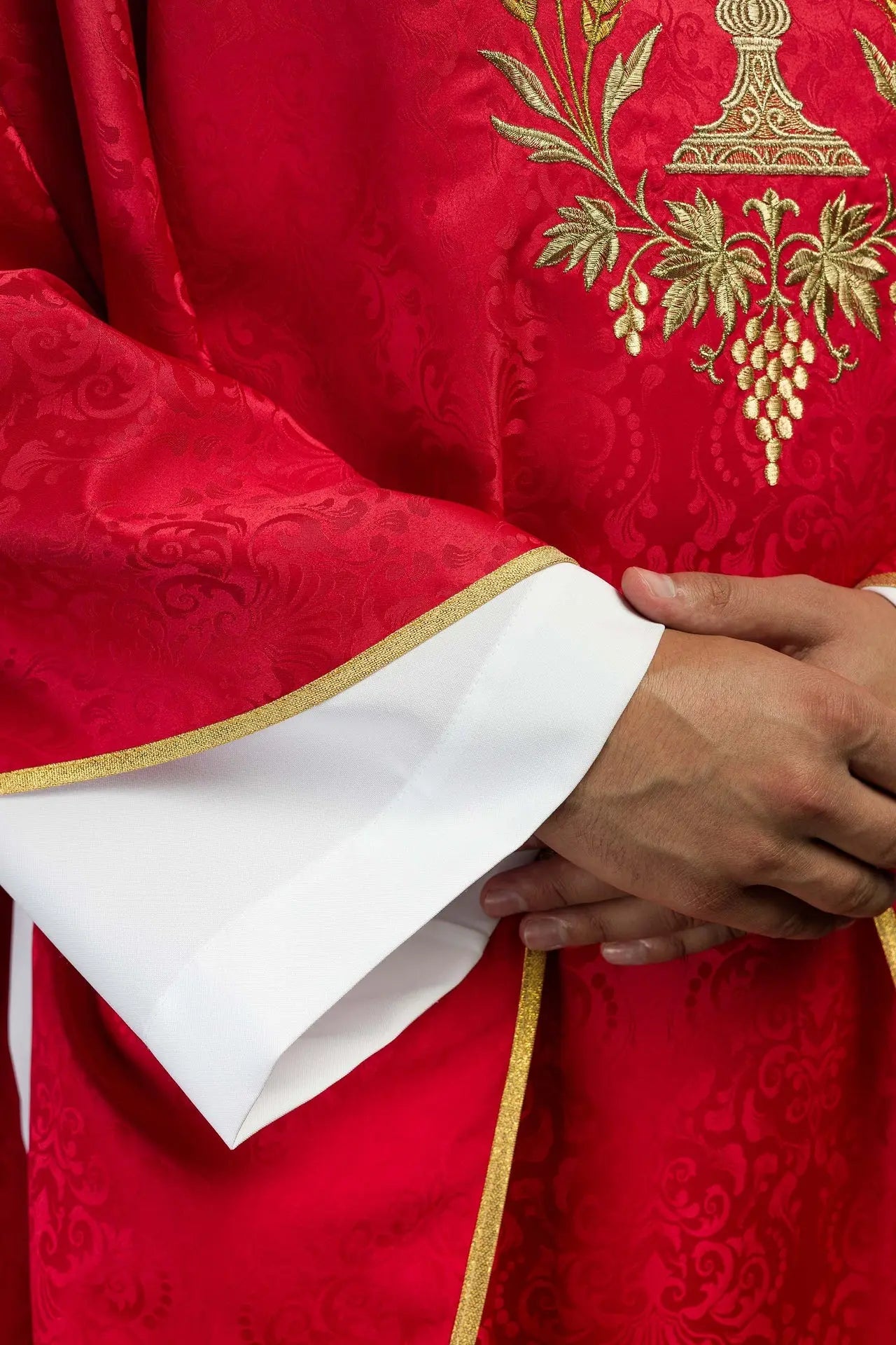Chasuble liturgique rouge avec un calice brodé et une hostie sur tissu jacquard