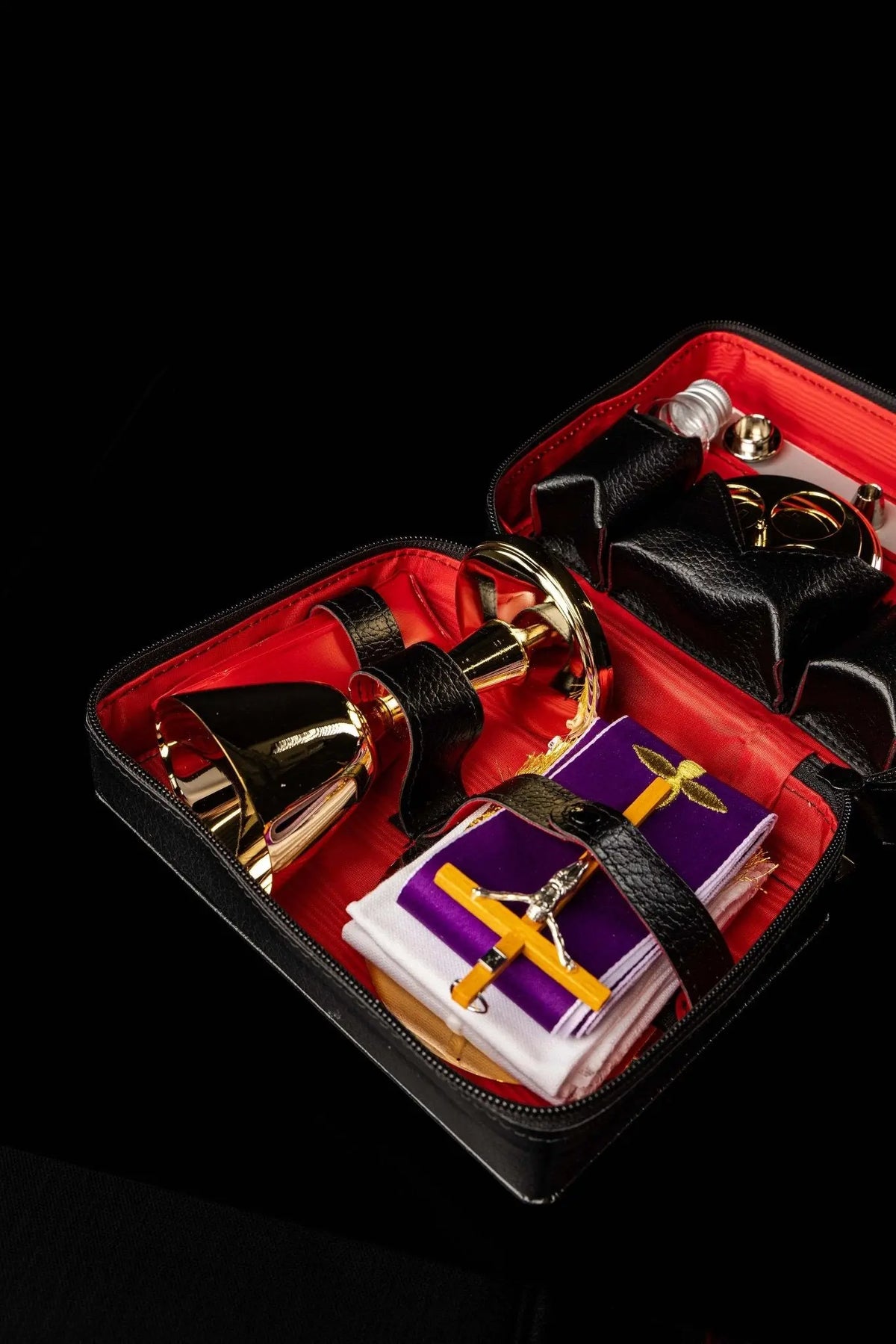 Valise de mission avec équipement liturgique et longue bandoulière noire, ouverte avec son contenu