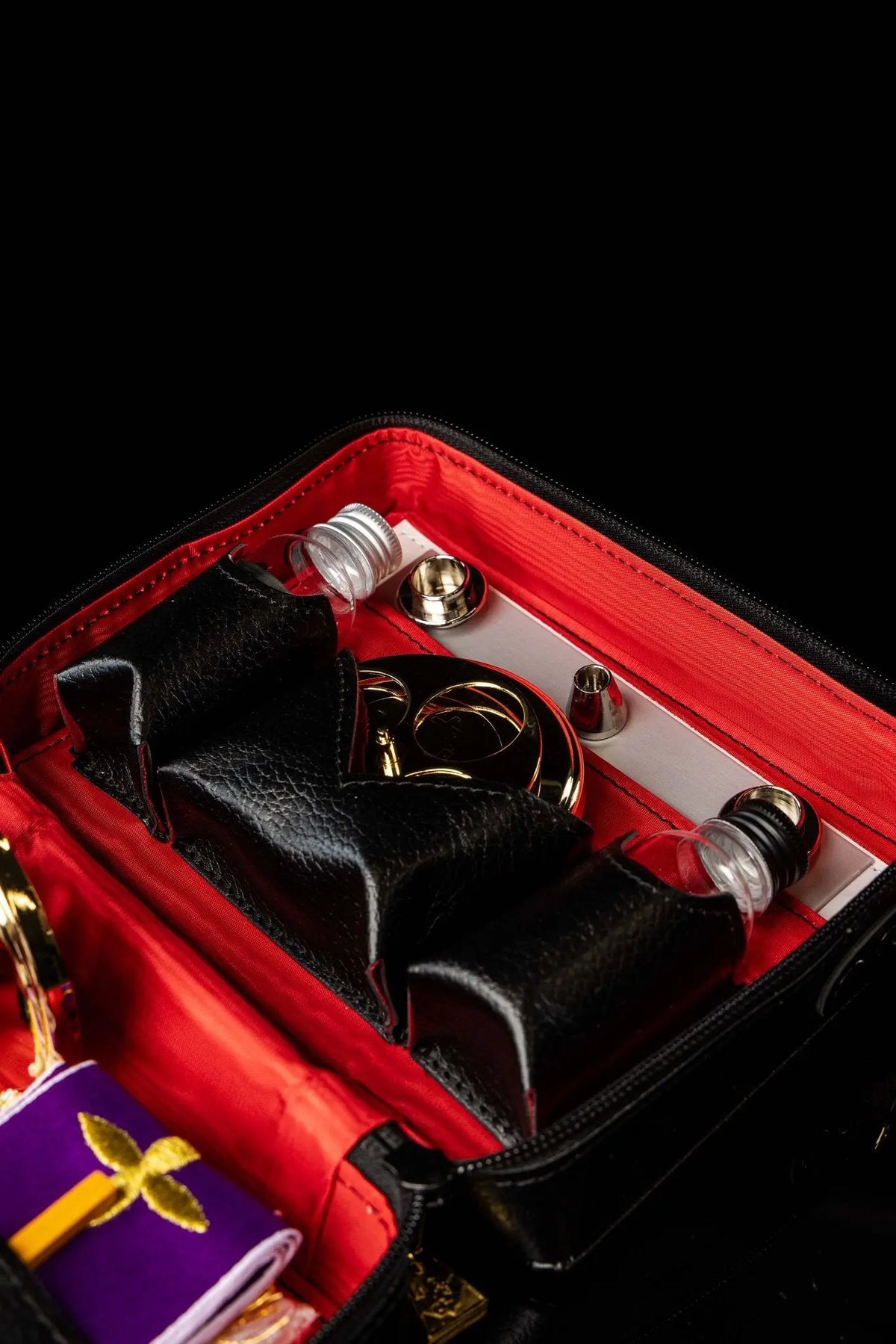 Valise de mission noire avec équipement liturgique, gros plan sur les accessoires métalliques