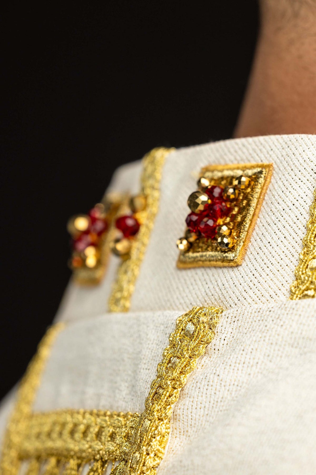 Écru chasuble ornée de pierres naturelles, motifs rouges et dorés en gros plan