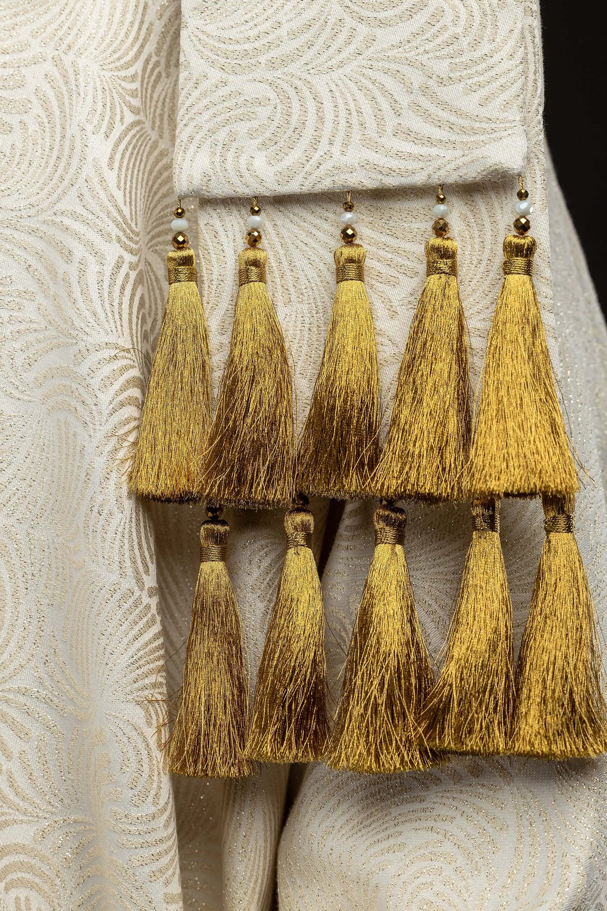 Écru chasuble avec glands dorés, détail du tissu jacquard et des glands