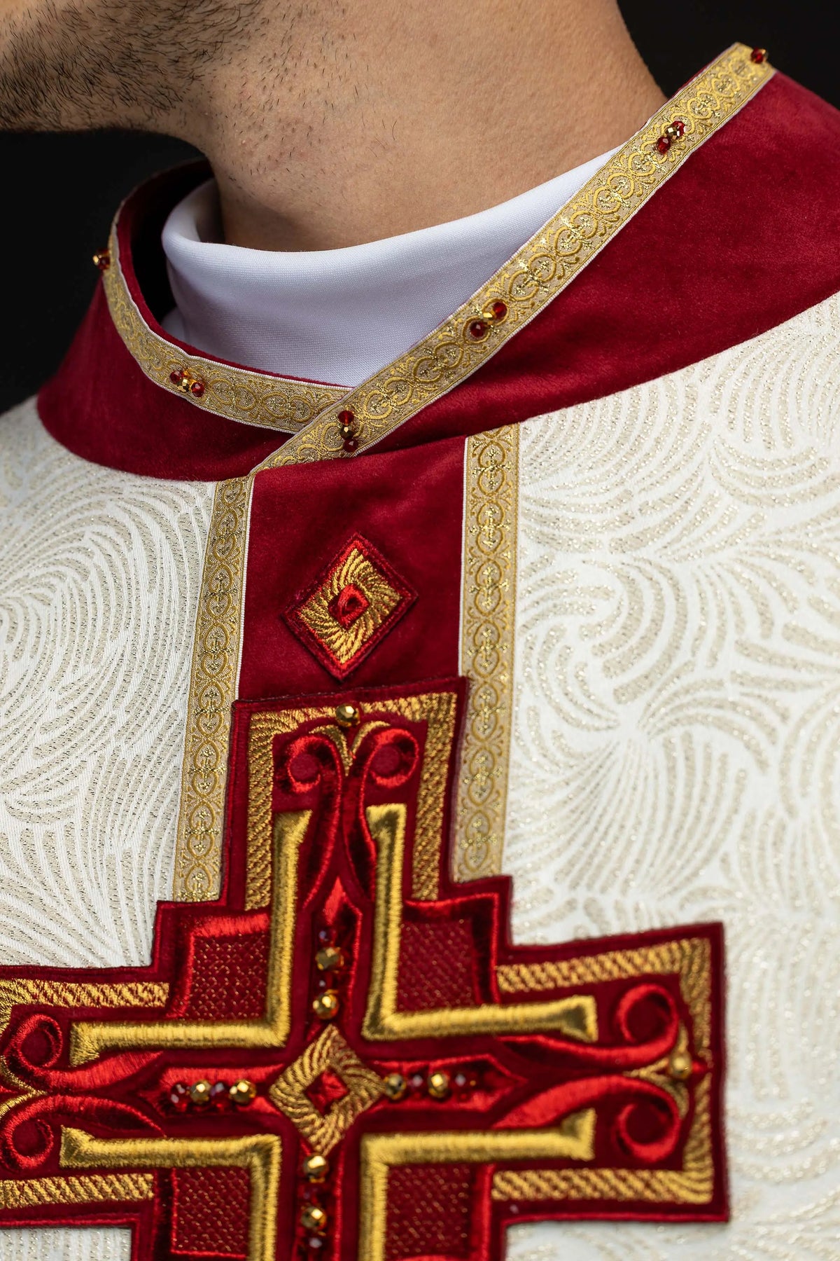 Écru chasuble avec croix brodée et pierres naturelles, gros plan sur le col rouge et la croix