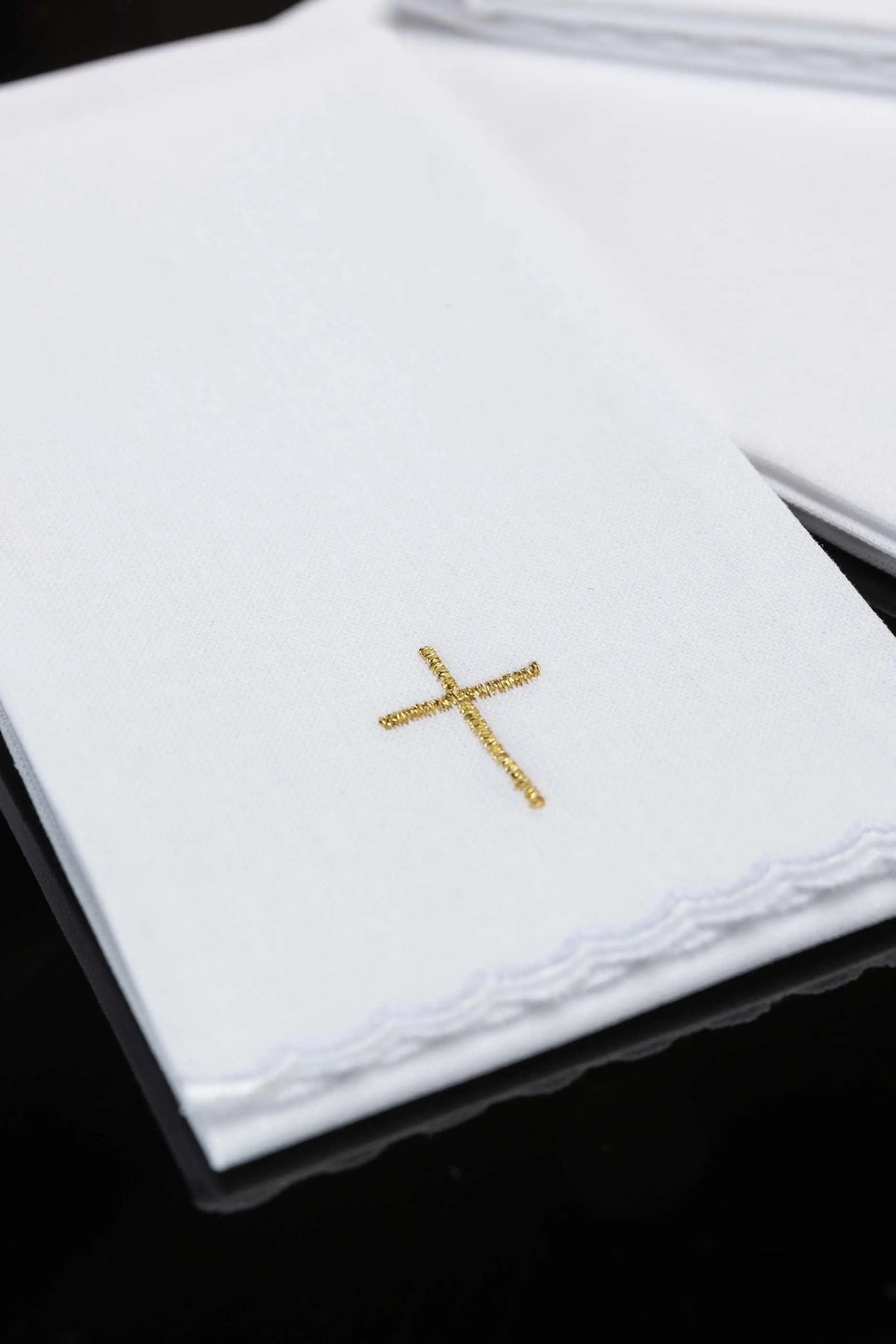 Blanc purificatoire avec croix brodée dorée, gros plan sur la broderie et la bordure