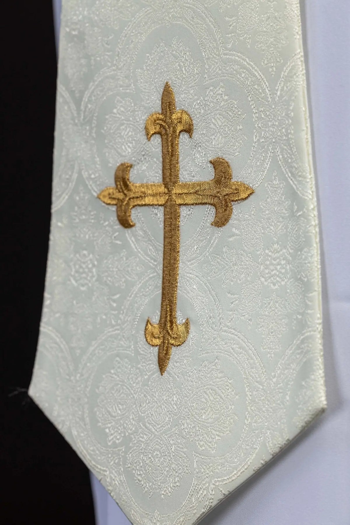 Écru étole sacerdotale avec croix brodée dorée, gros plan sur la pointe