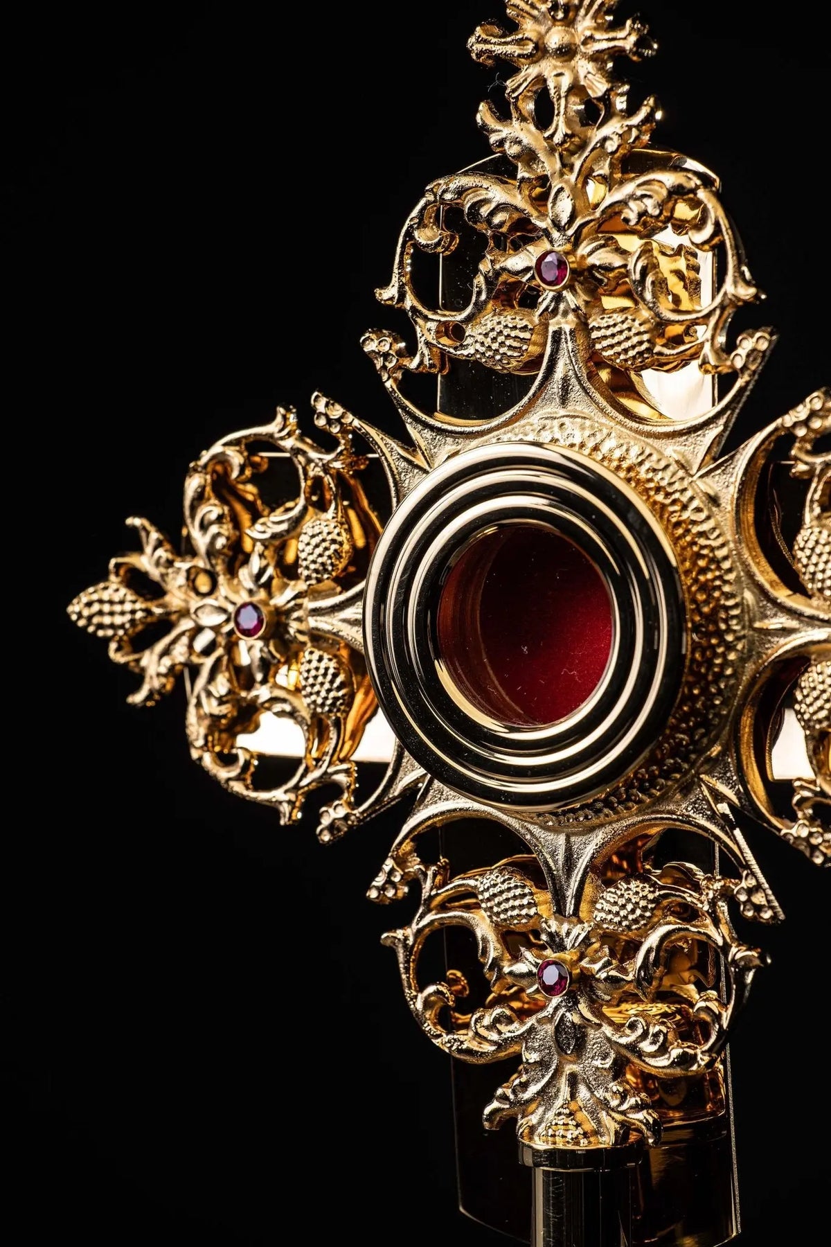 Doré reliquaire en laiton avec motifs floraux ajourés et cabochon rouge, gros plan en légère perspective
