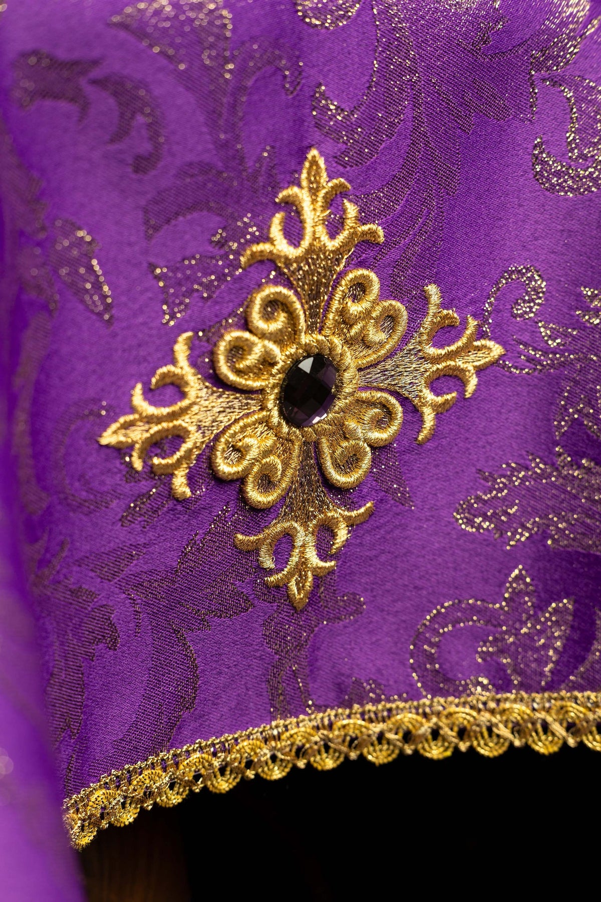 Violet voile de calice brodé d’une croix, gros plan sur la broderie
