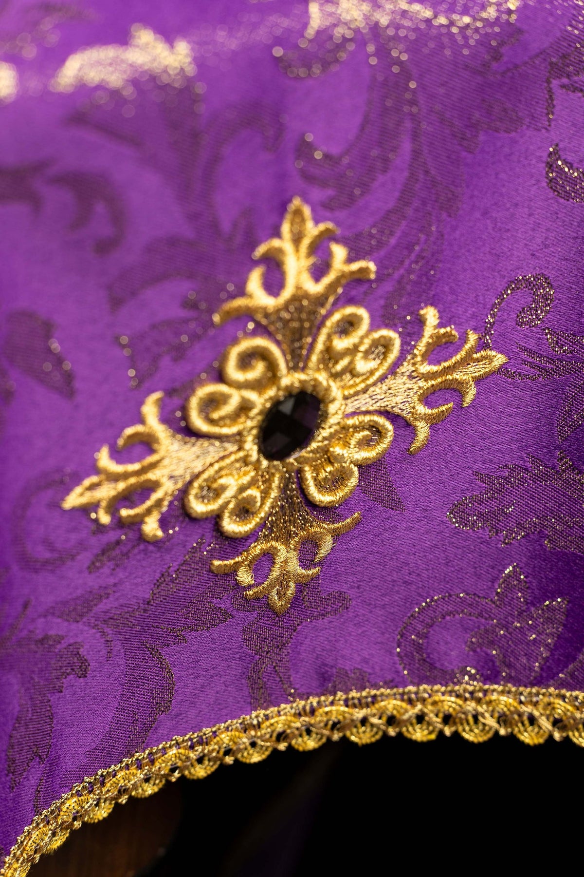 Violet voile de calice brodé d’une croix, gros plan sur le motif doré