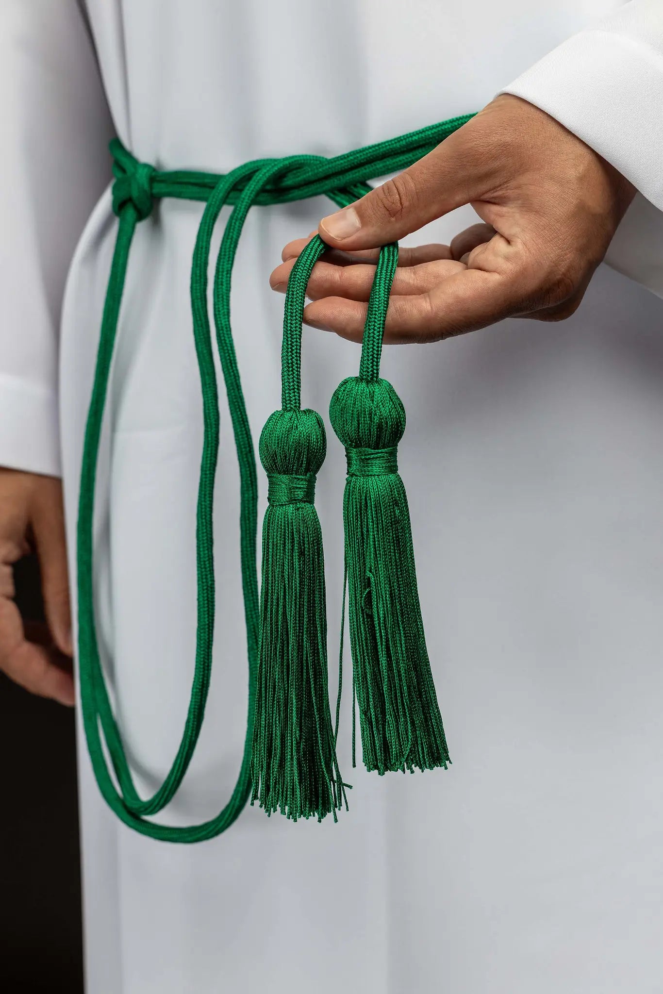Green liturgical cincture with decorative tassels, made from braided cord.