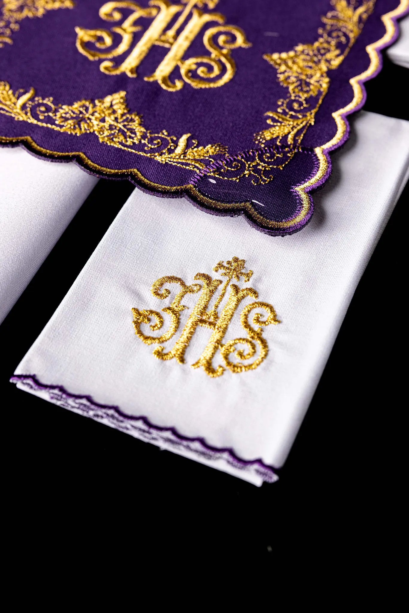 Purple chalice linen set with gold IHS embroidery, vine leaves, and wheat sheaves. Includes a purple pall, white corporal with IHS, and white purificator and lavabo towel with gold crosses and purple scalloped edges.