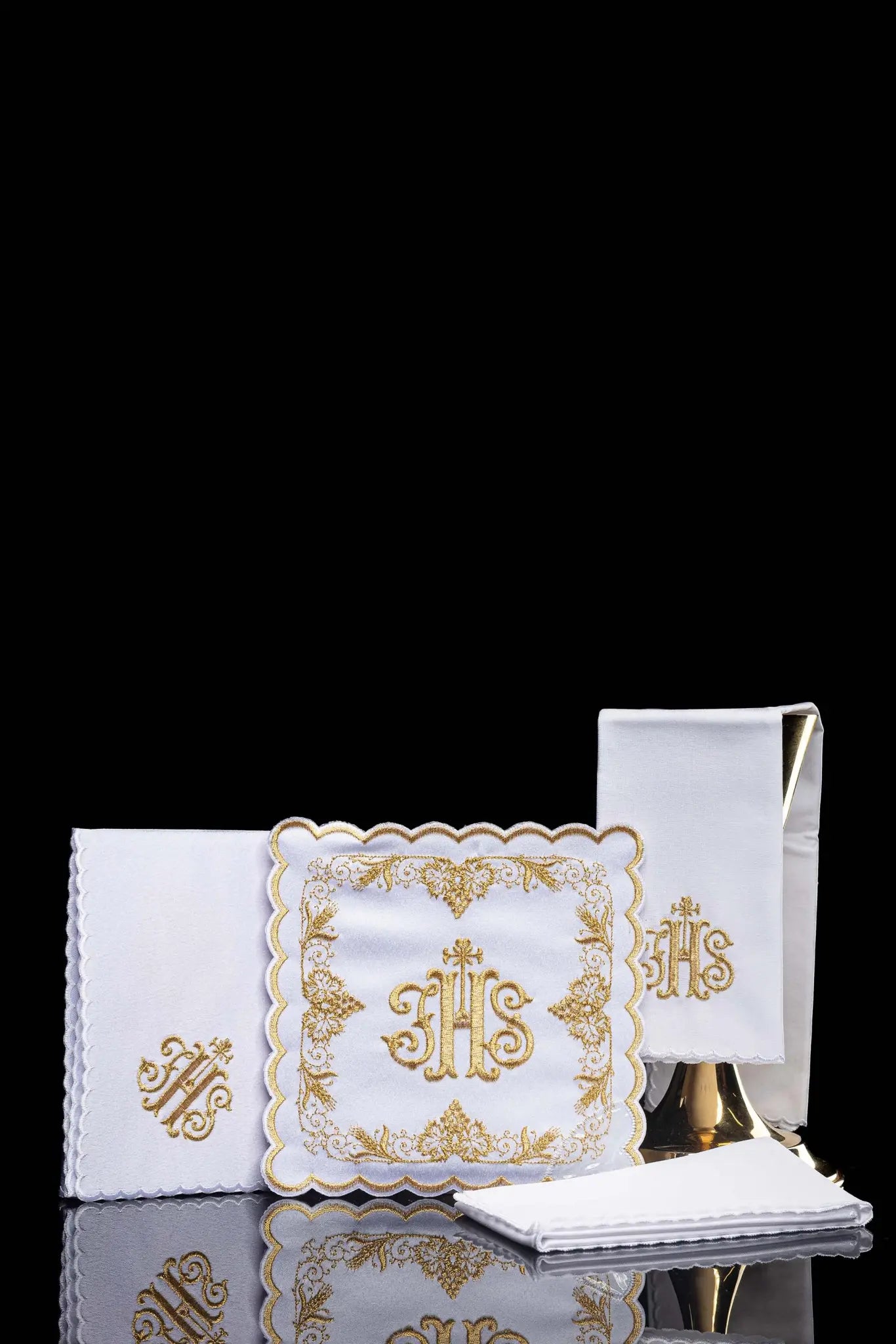 White chalice linen set with IHS embroidery on pall, purificator, and lavabo towel.