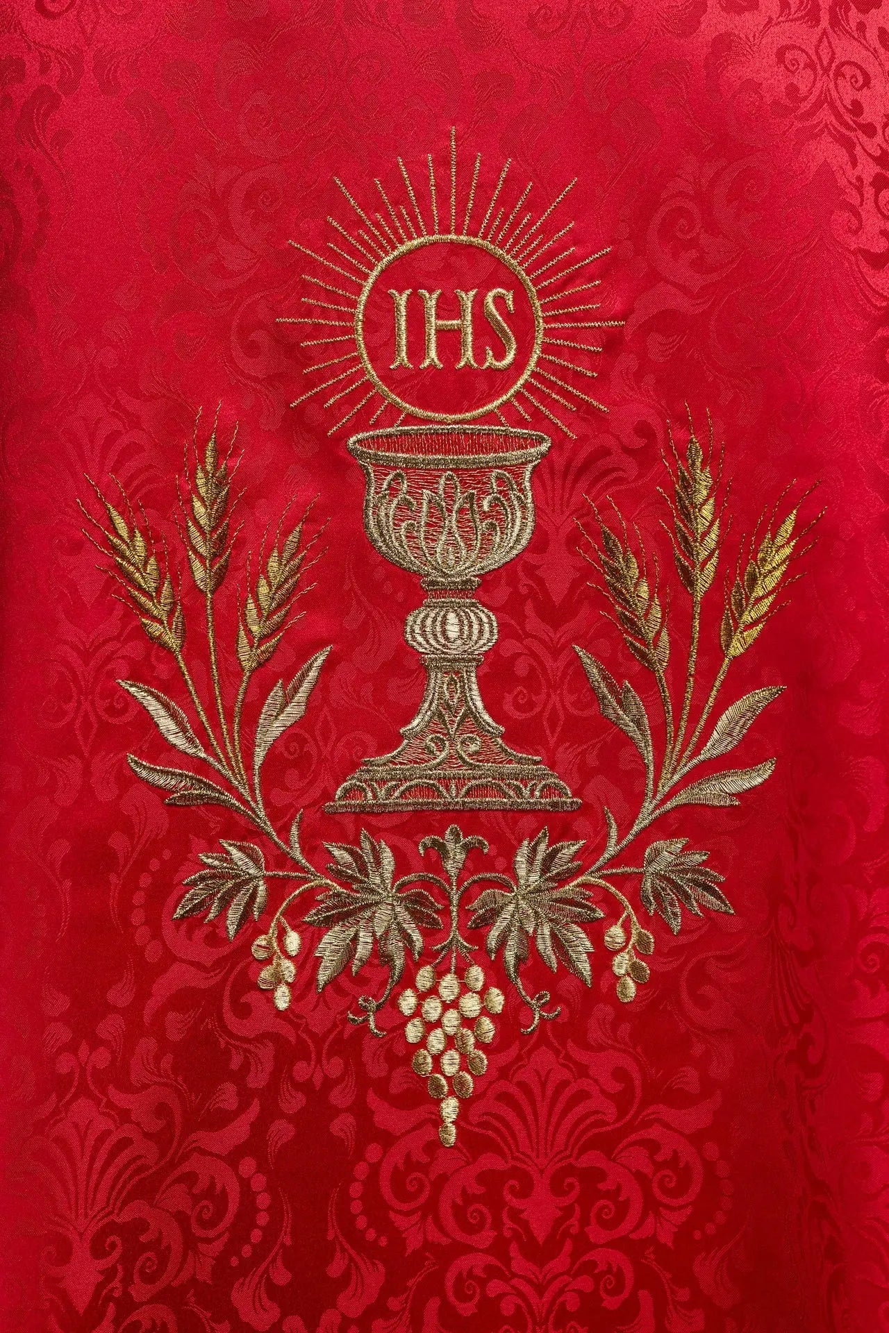 Chasuble liturgique rouge avec un calice brodé et une hostie sur tissu jacquard