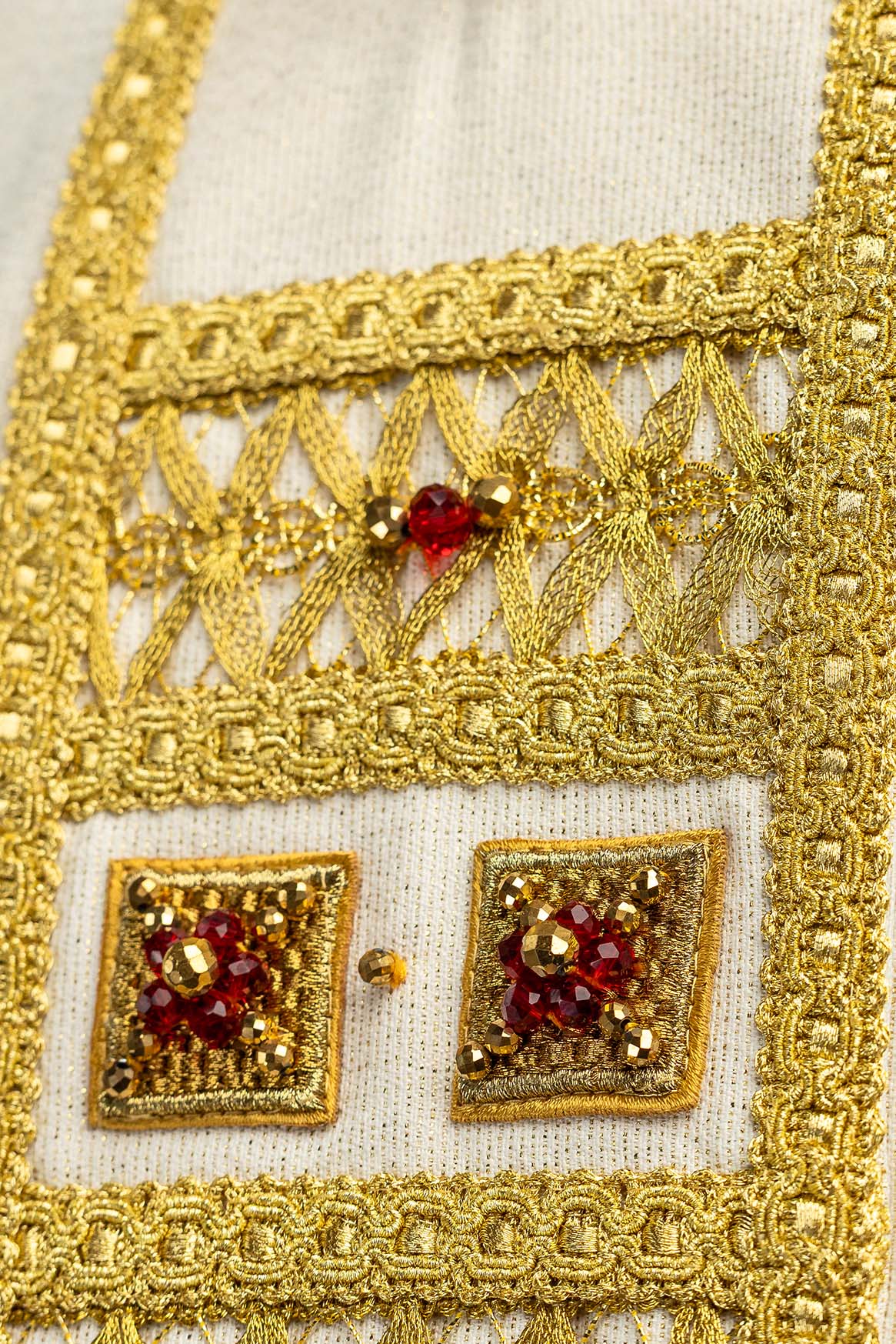 Chasuble écru ornée de pierres naturelles, gros plan de la broderie dorée ajourée