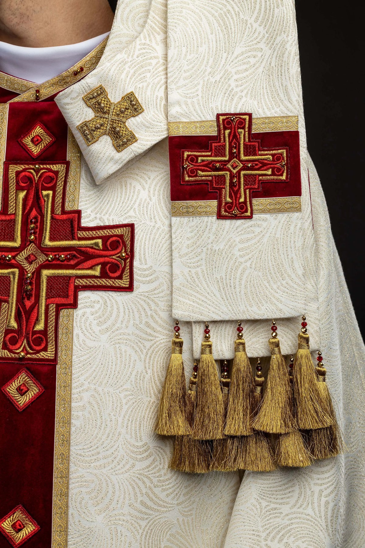 Écru chasuble avec croix brodée et pierres naturelles, gros plan sur les glands et la croix