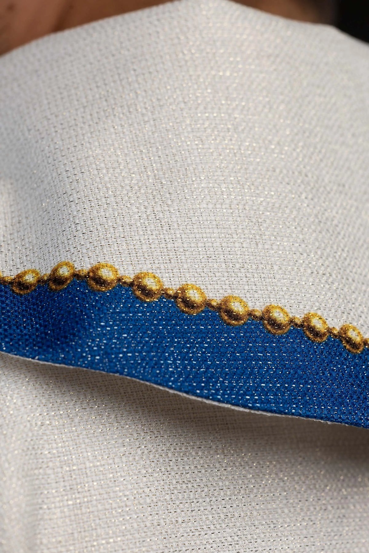 Écrue chasuble avec bordure bleue et perles dorées, détail du tissu
