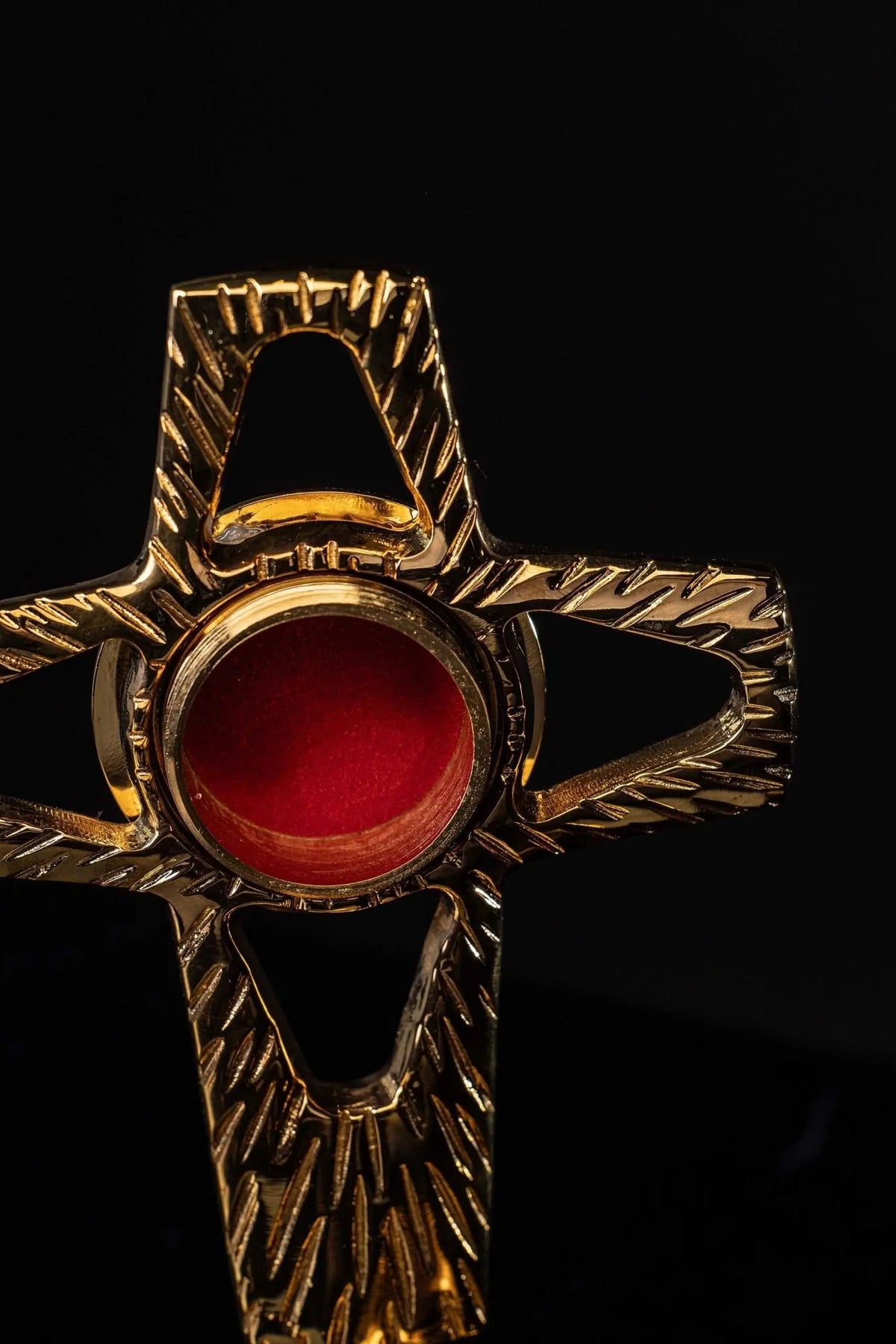 Doré reliquaire en forme de croix en laiton, ouverture circulaire rouge et rayons gravés, gros plan de face