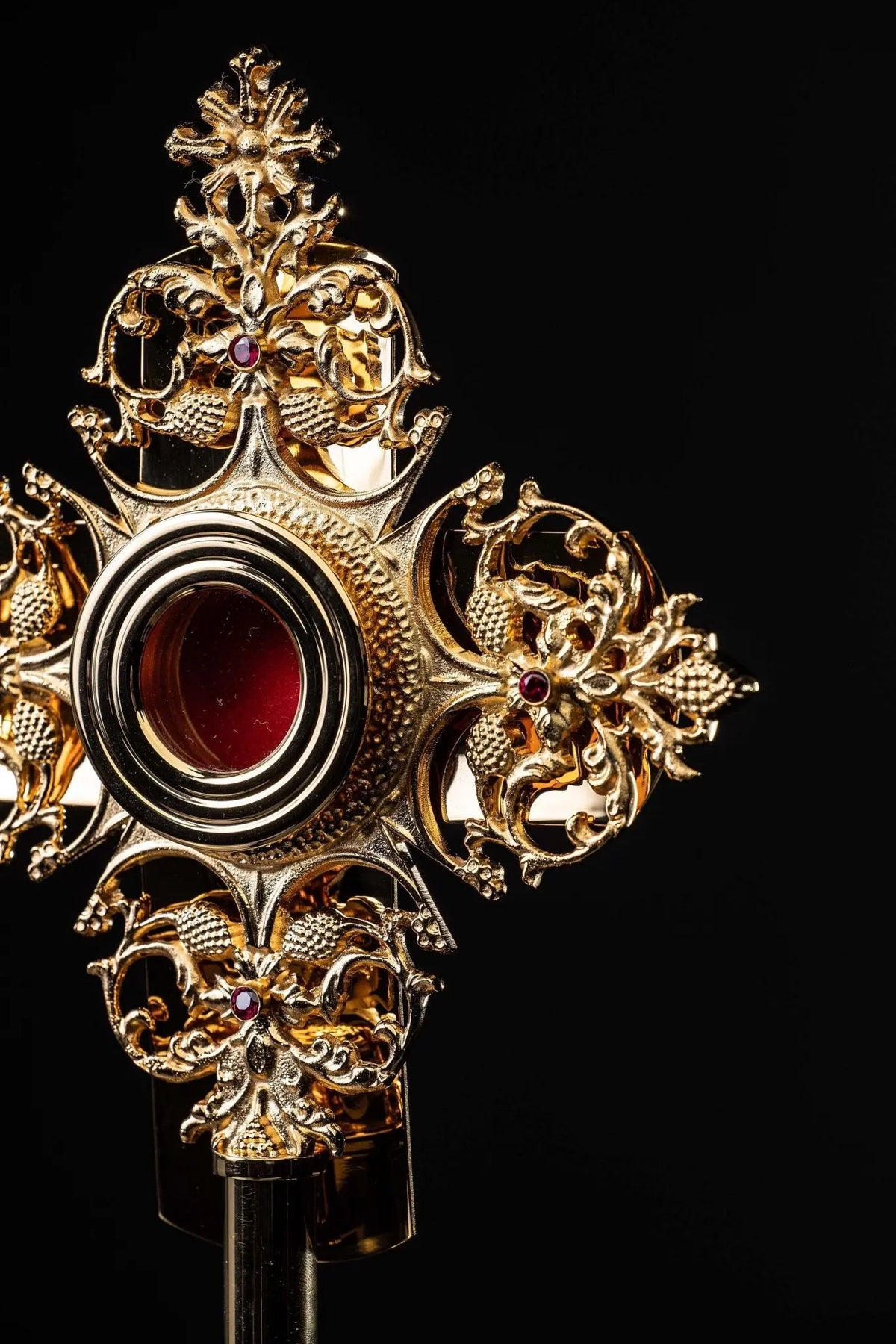 Doré reliquaire en laiton avec ornements floraux et cabochon rouge, vue rapprochée de trois quarts