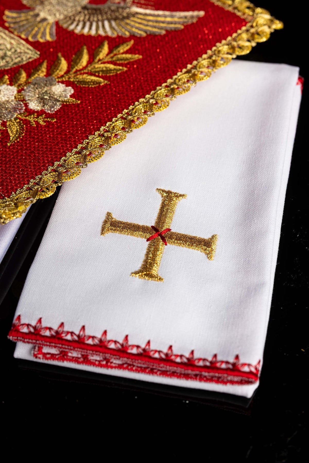 Linges de calice rouges avec croix dorée brodée et bordure rouge, vue rapprochée