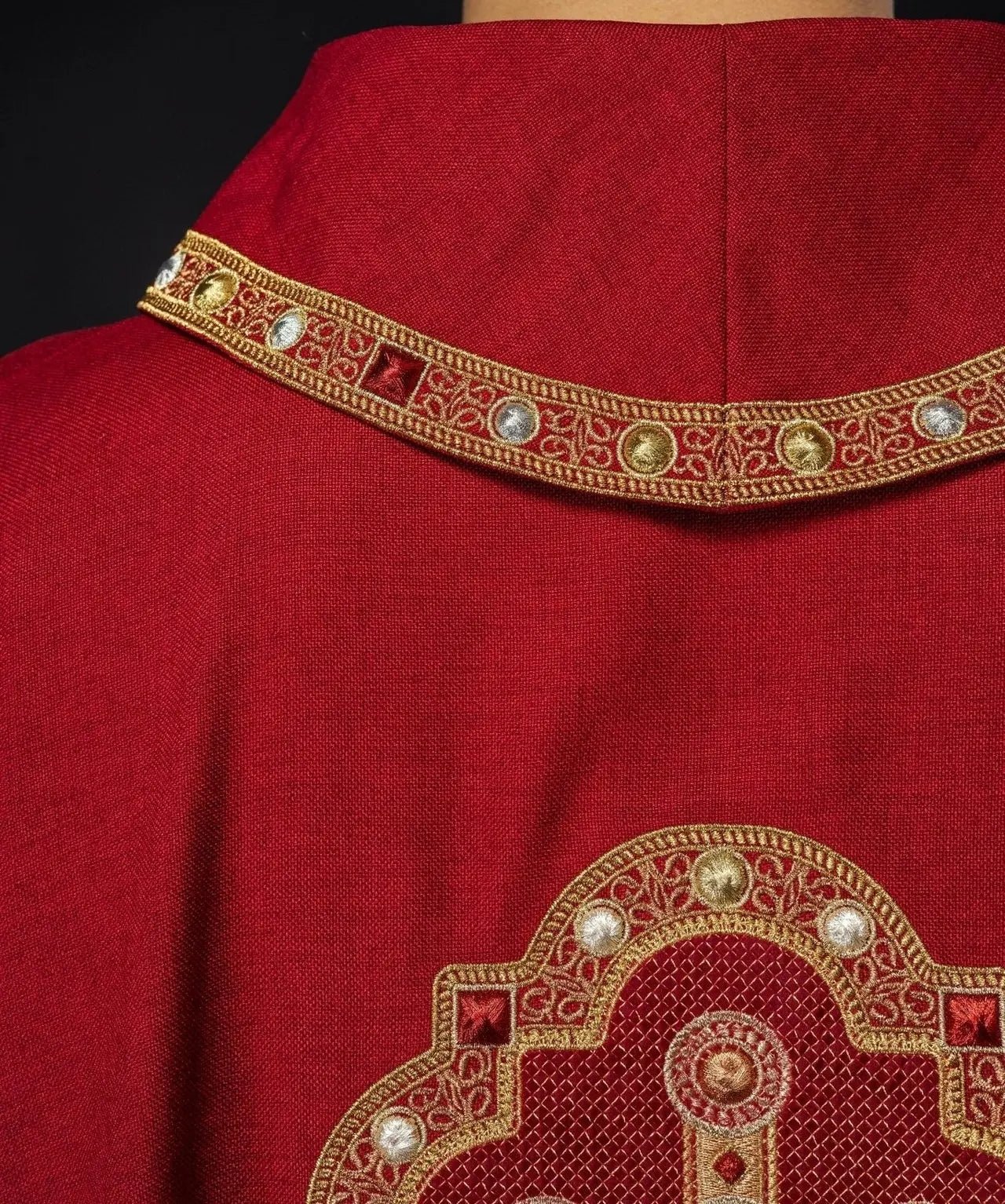Chasuble rouge avec passepoil brodé sur le col et autour de la broderie de la croix