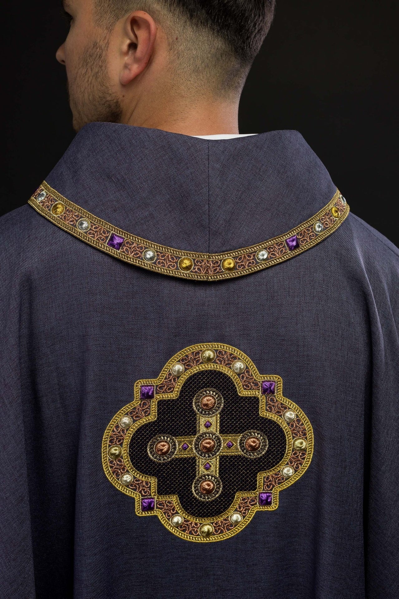 Ornat w kolorze fioletowym z haftowaną lamówką na kołnierzu i wokół haftu krzyża