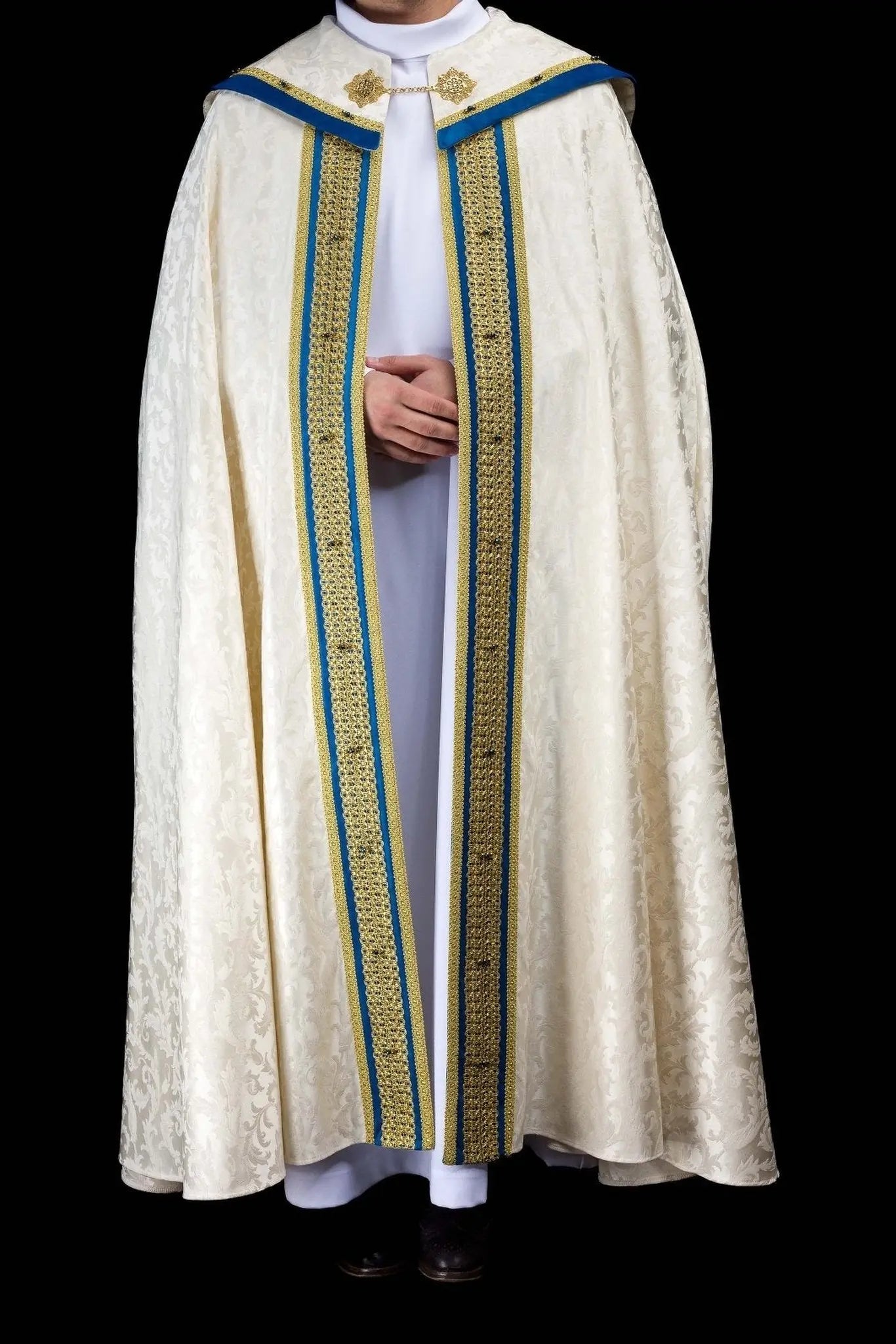 Ecru Marian cope with natural stones and blue velvet trim, part of the Handmade Collection, featuring an ornate metal clasp and gold tassel.